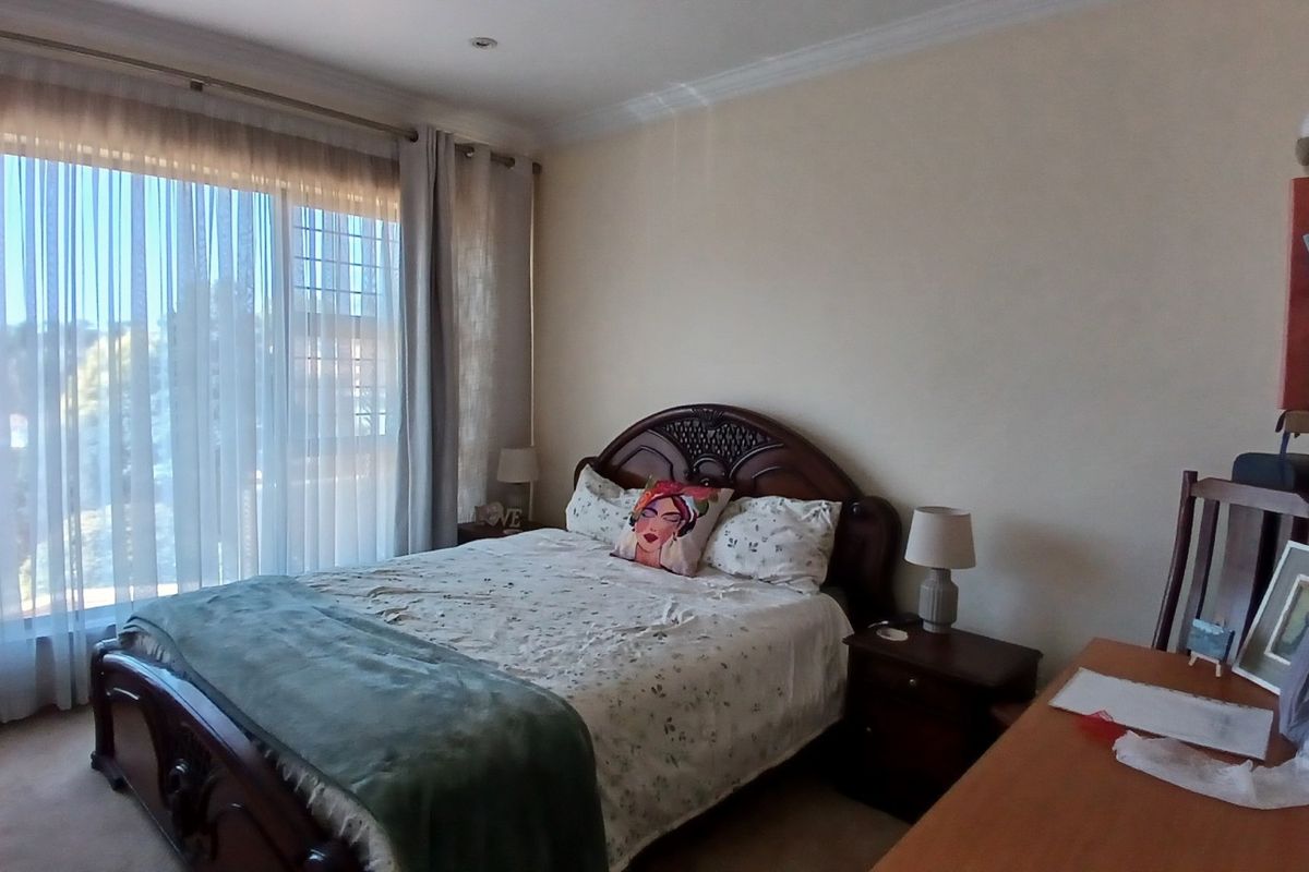 A well-lit bedroom featuring carpeted flooring, recessed ceiling lights, and a large sliding glass door providing access to the exterior.