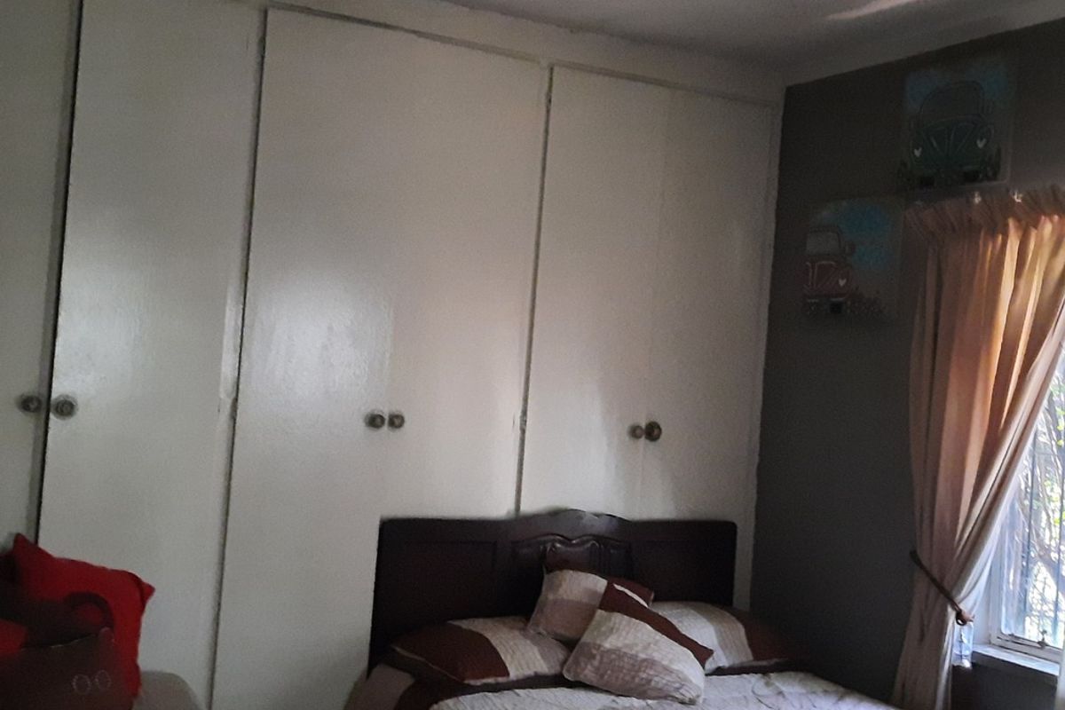 A bedroom featuring floor-to-ceiling built-in cupboards and a central ceiling fan, providing functional storage and lighting.