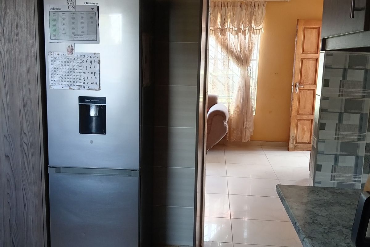 A kitchen area featuring built-in cabinetry and tiled flooring, with a clear view through to an adjacent living space.