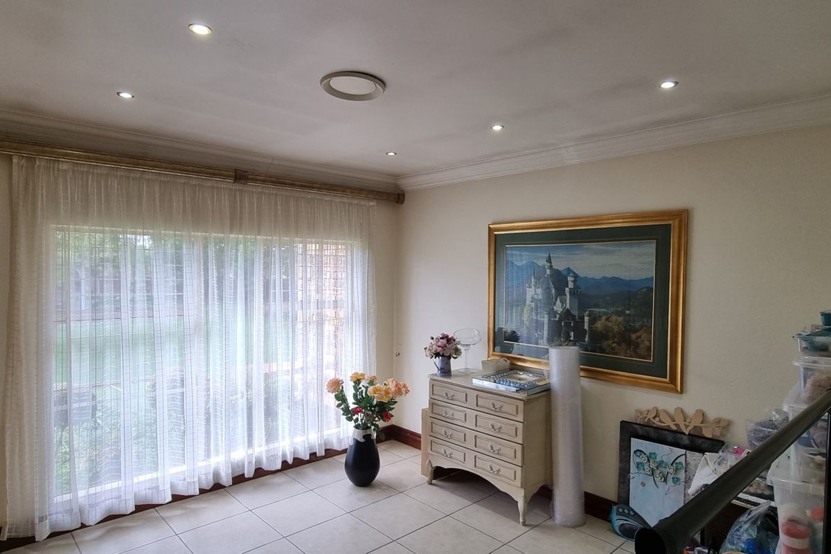 A bright living area featuring tiled flooring, recessed downlighting, and decorative ceiling coving, offering a neutral canvas for interior design.