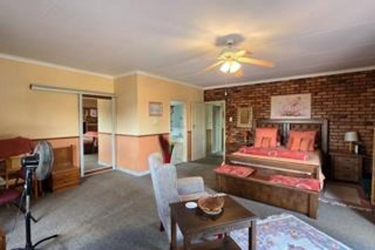 Spacious bedroom featuring a prominent exposed brick feature wall, built-in sliding door closets, and direct access to an en-suite bathroom.