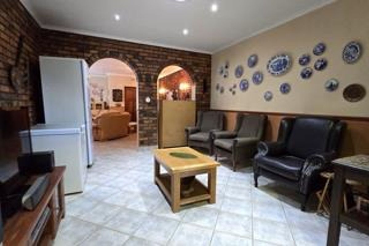 A living area featuring exposed brick walls, arched doorways leading to adjacent rooms, and tiled flooring throughout.
