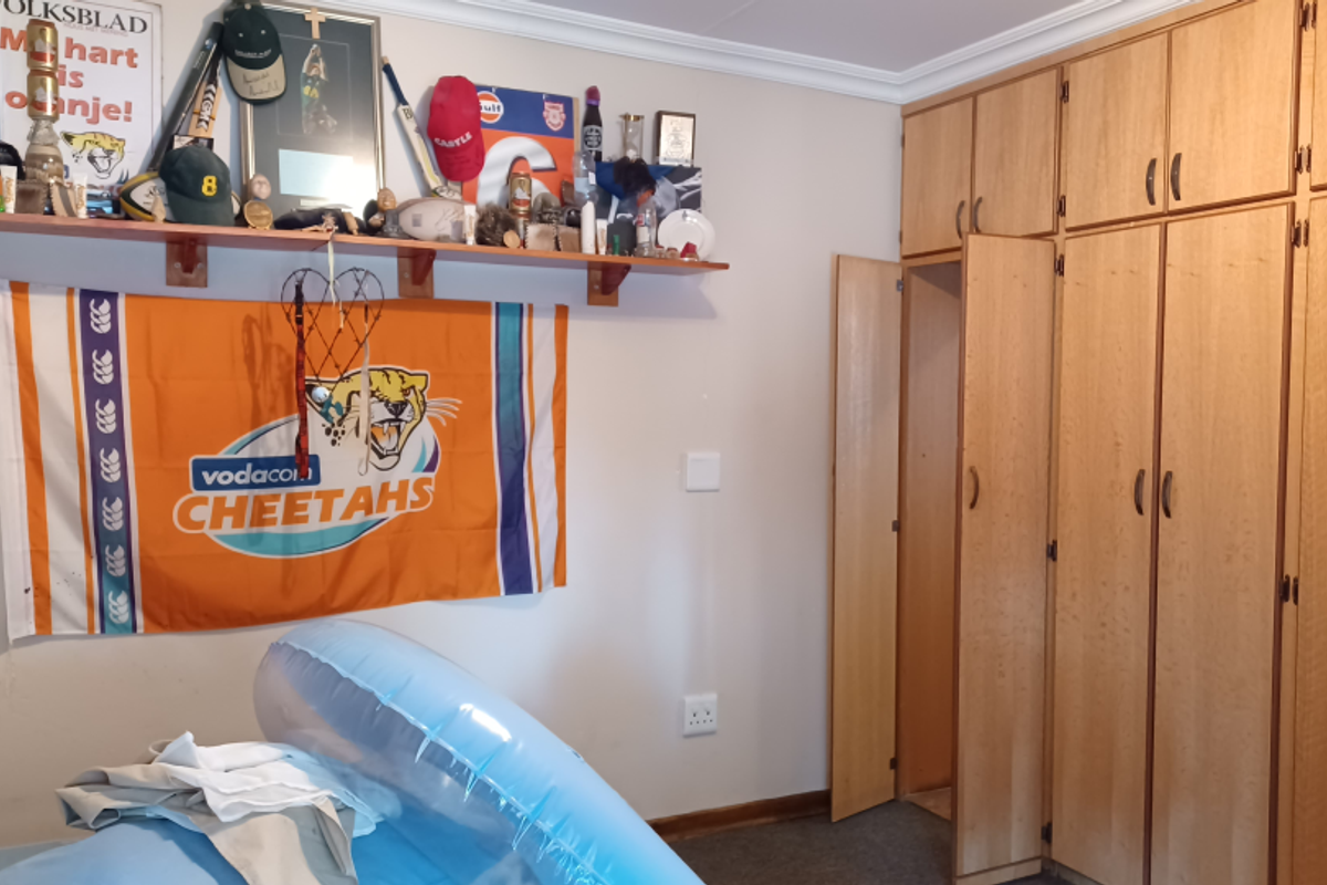 Bedroom featuring built-in wooden cabinetry with overhead storage and a wall-mounted display shelf.