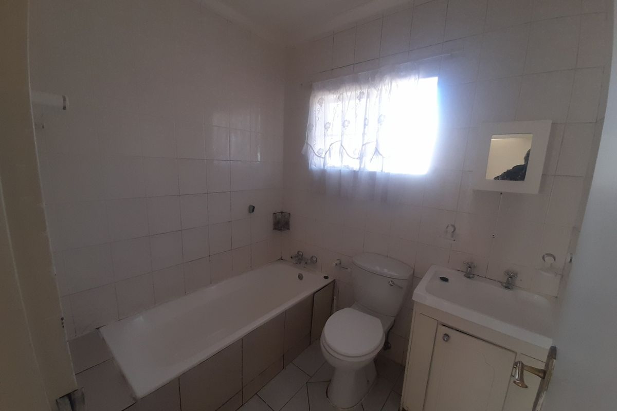 A functional bathroom featuring a standard bathtub, toilet, and vanity basin with tiled walls and flooring.