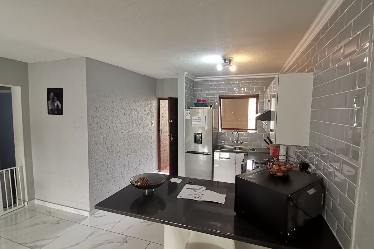 A functional kitchen featuring a breakfast bar, subway tile backsplash, and tiled flooring, providing a practical layout for daily meal preparation.
