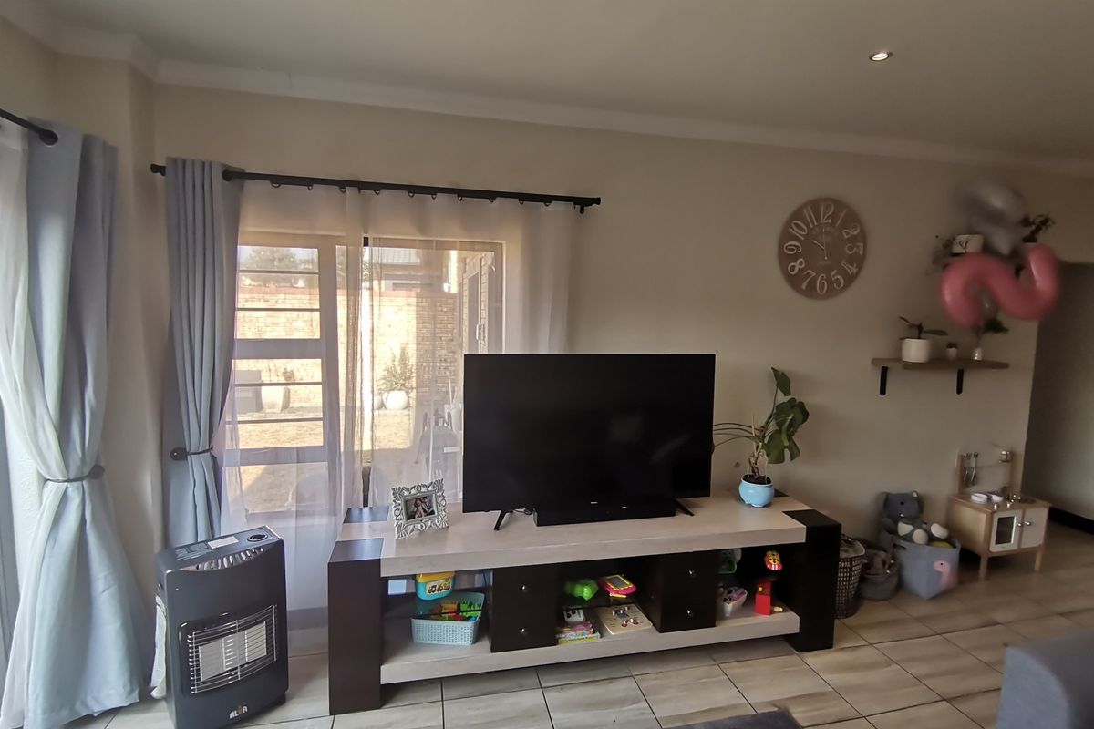 A living room featuring tiled flooring, recessed ceiling lighting, and a large window with access to the exterior.