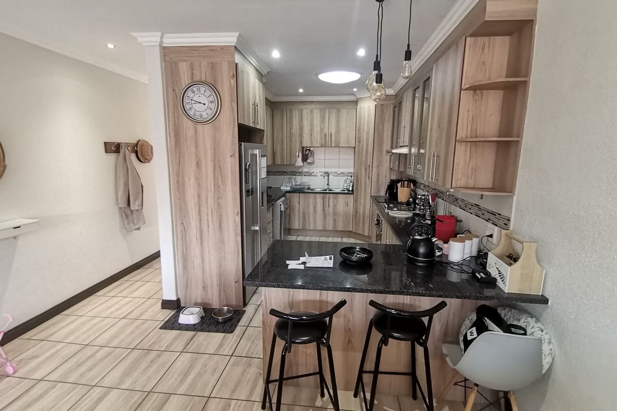 Modern kitchen featuring wood-look cabinetry, granite countertops, a breakfast bar, and recessed lighting, seamlessly integrated into the open-plan living area.