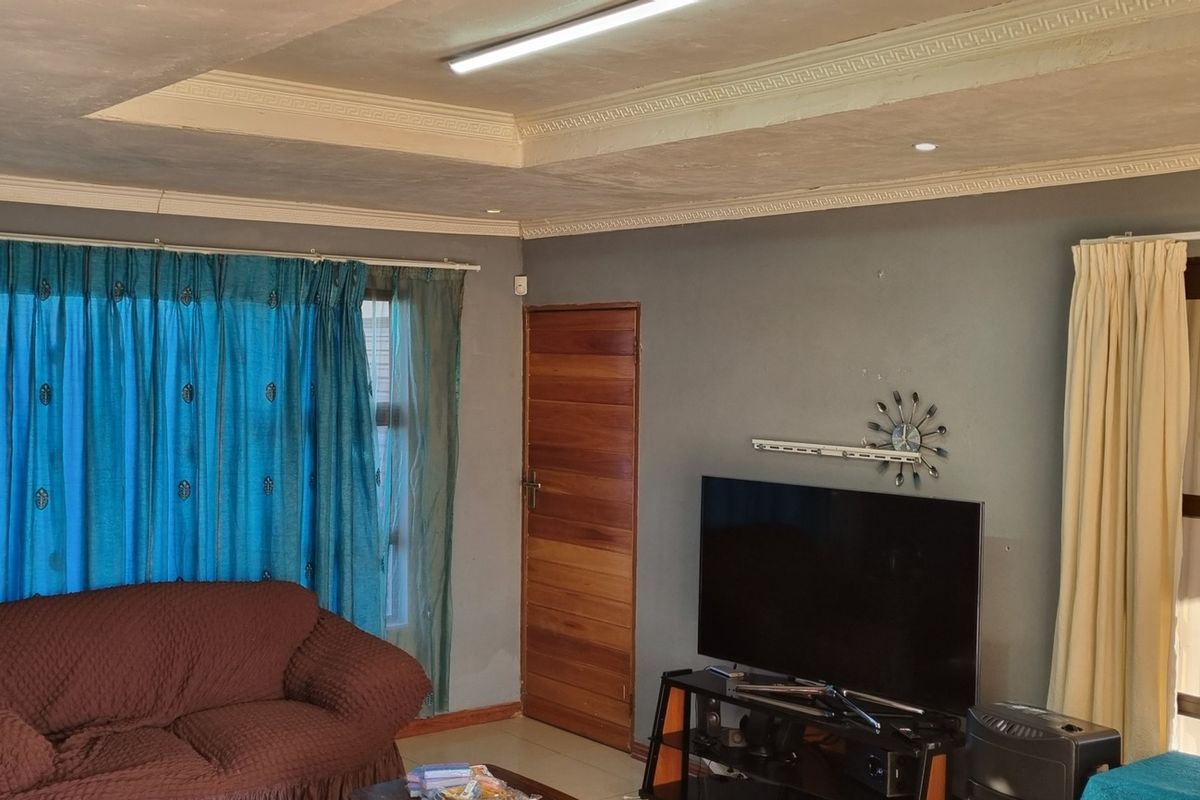 A living room featuring a tray ceiling with decorative molding, a wooden door, and large windows with curtains.