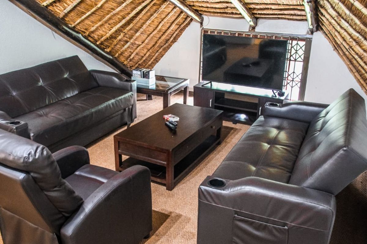 Cozy living area featuring a traditional thatched roof with exposed timber rafters, creating a rustic and warm atmosphere.