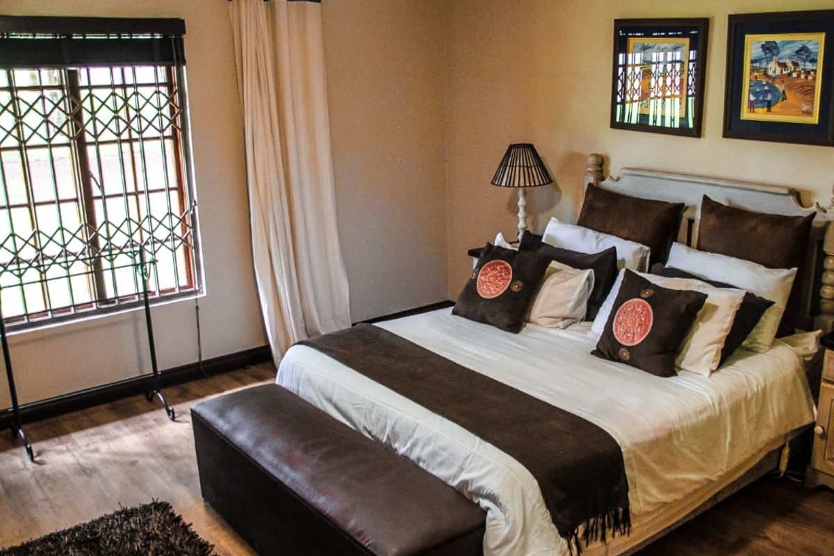 A well-maintained bedroom featuring laminate flooring, neutral wall tones, and a window fitted with a security gate.
