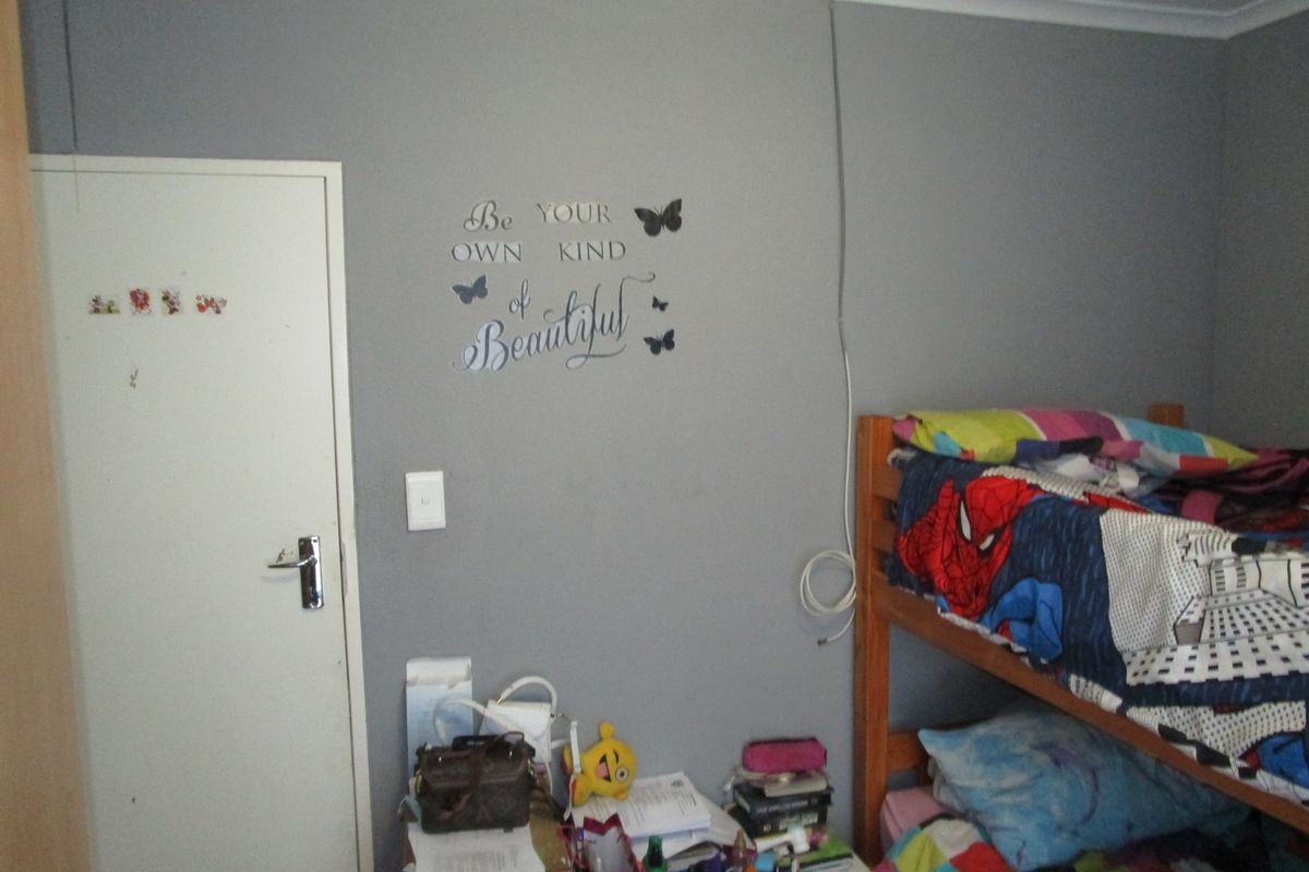 A bedroom featuring grey painted walls, a standard door, and an exposed electrical cable running down the wall.