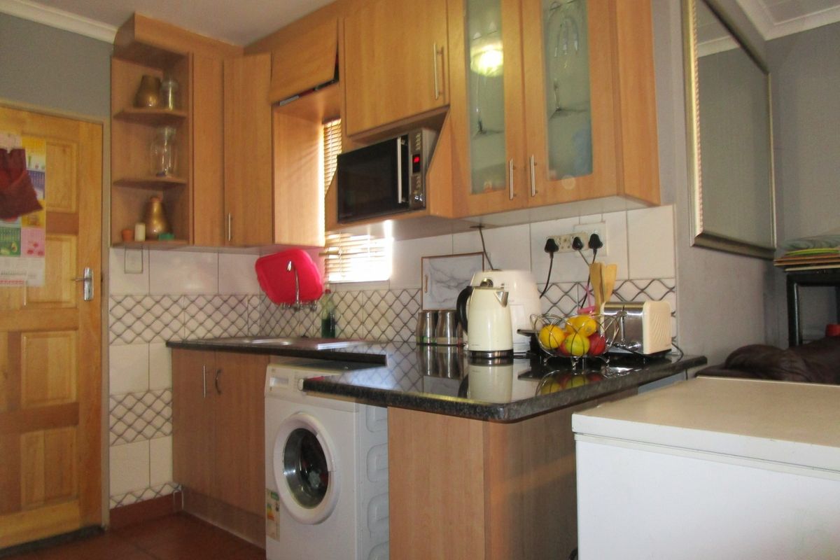 Compact kitchen featuring light wood cabinetry, granite-look countertops, tiled backsplash, and integrated space for a washing machine.