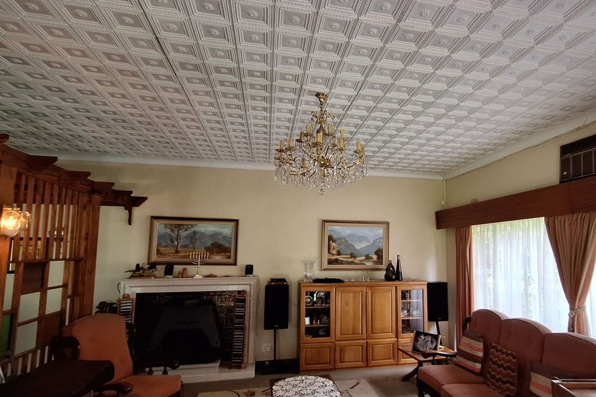 Spacious living room featuring a traditional fireplace, decorative ceiling tiles, and a large window with integrated air conditioning unit.