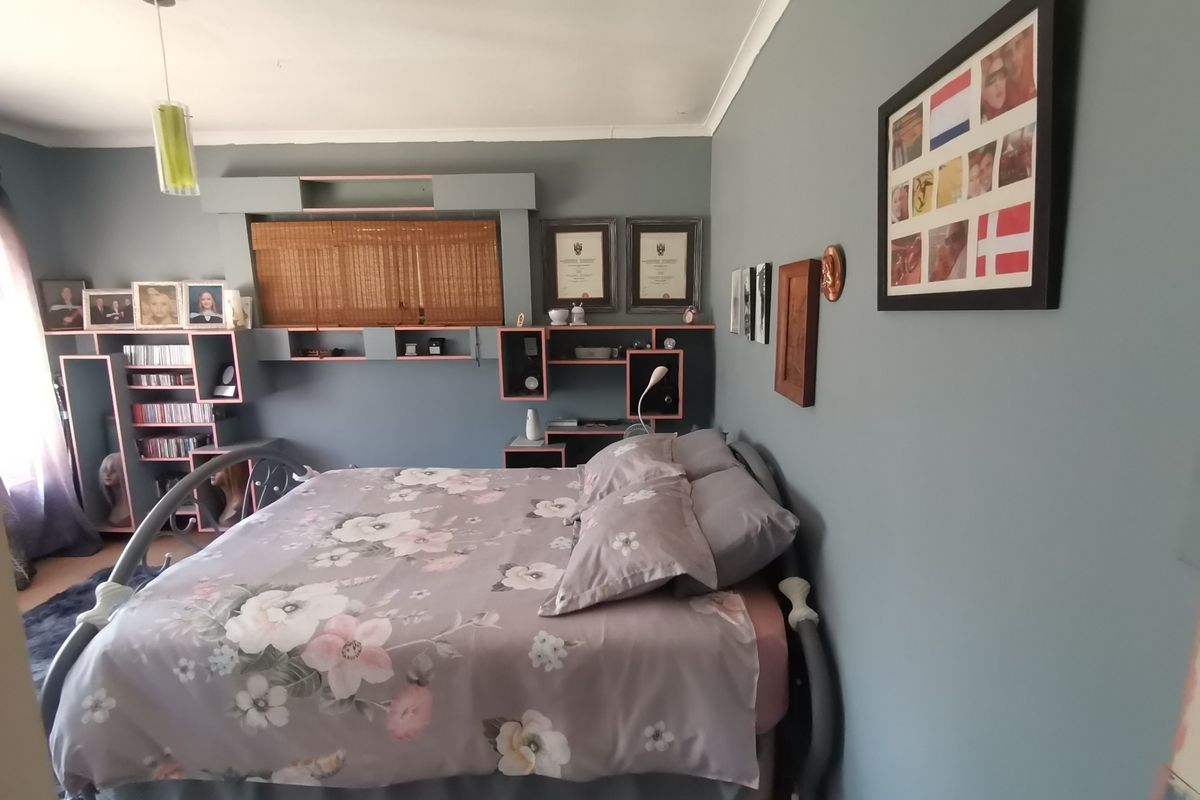 A bedroom featuring built-in shelving and cabinetry units, providing integrated storage solutions against a painted feature wall.