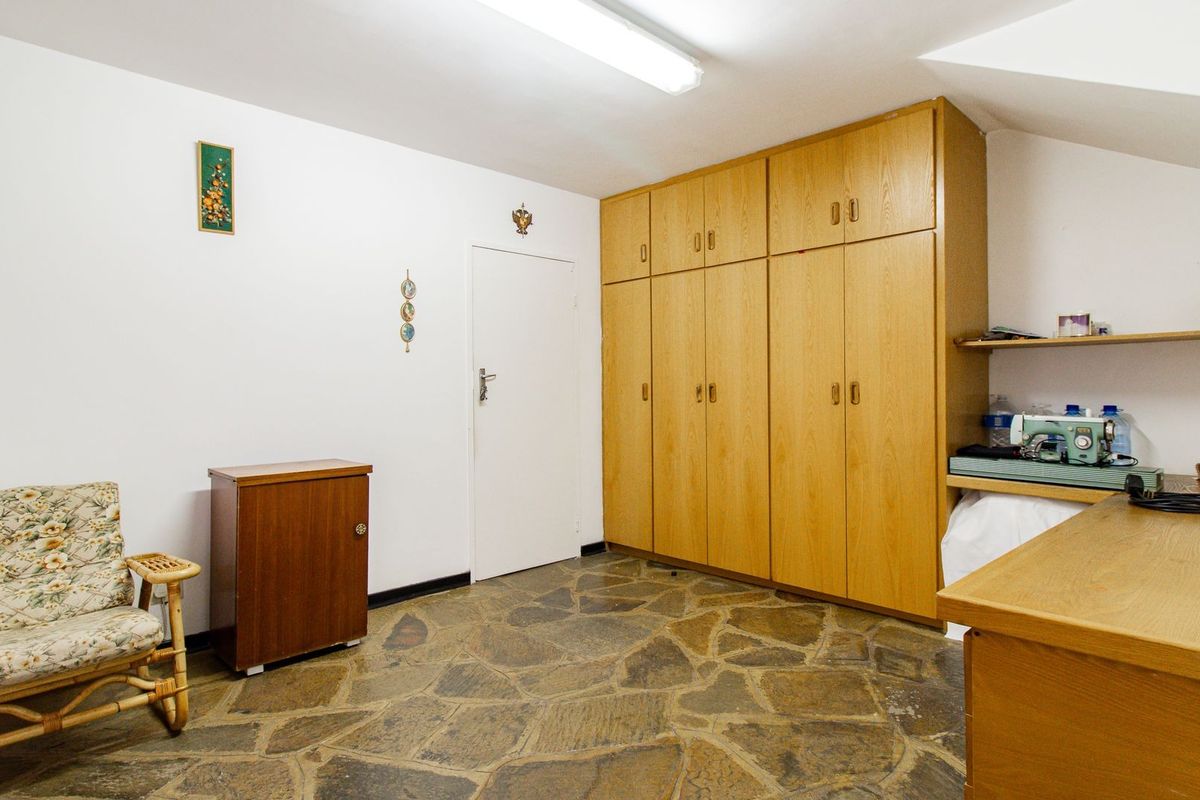 A bedroom featuring built-in wooden cabinetry, unique stone flooring, and a sloped ceiling, offering functional storage space.