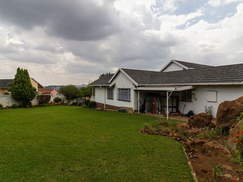 Spacious rear garden featuring a well-maintained lawn, rockery landscaping, and a covered patio area attached to the main house structure.