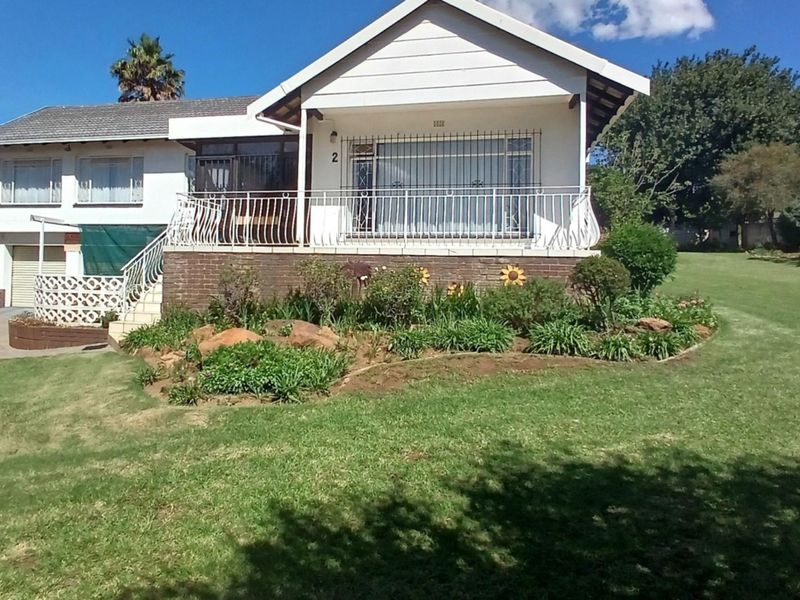 Front view of a single-story residential house featuring a brick base, tiled roof, security bars, and a well-maintained front garden with a driveway.
