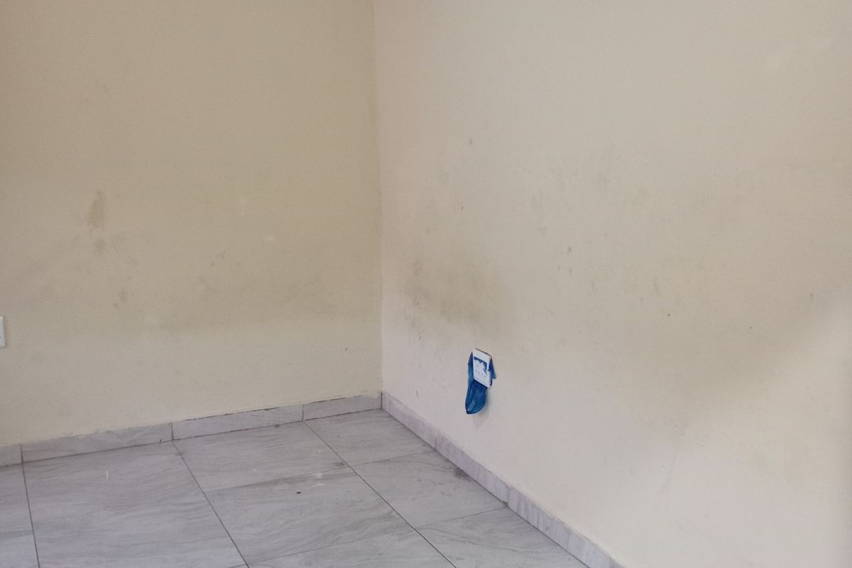 An empty bedroom featuring tiled flooring and coved ceilings, requiring cosmetic attention to wall surfaces and electrical fixtures.