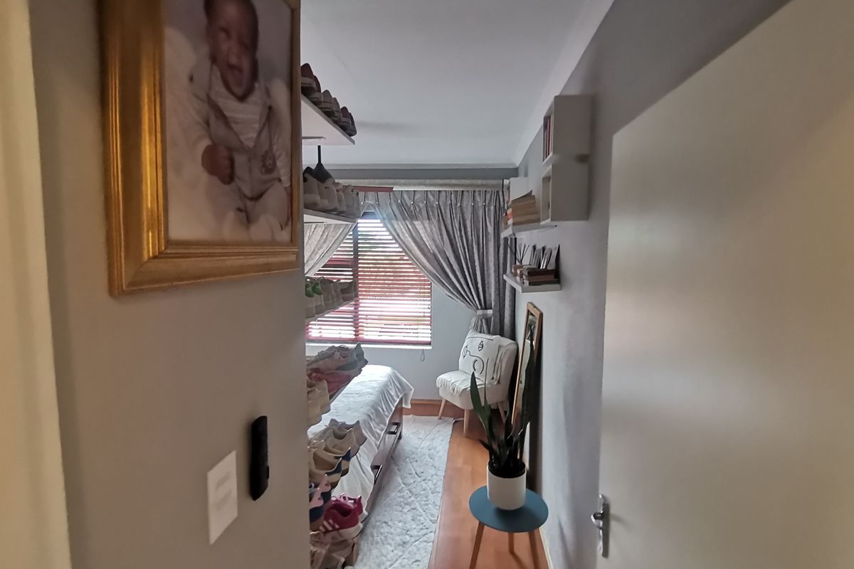 A view into a bedroom featuring wood-look flooring, a window with venetian blinds, and built-in shelving units.
