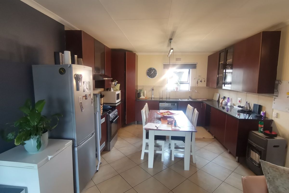 A functional kitchen featuring dark wood cabinetry, granite countertops, and tiled flooring, offering a practical layout for daily meal preparation.