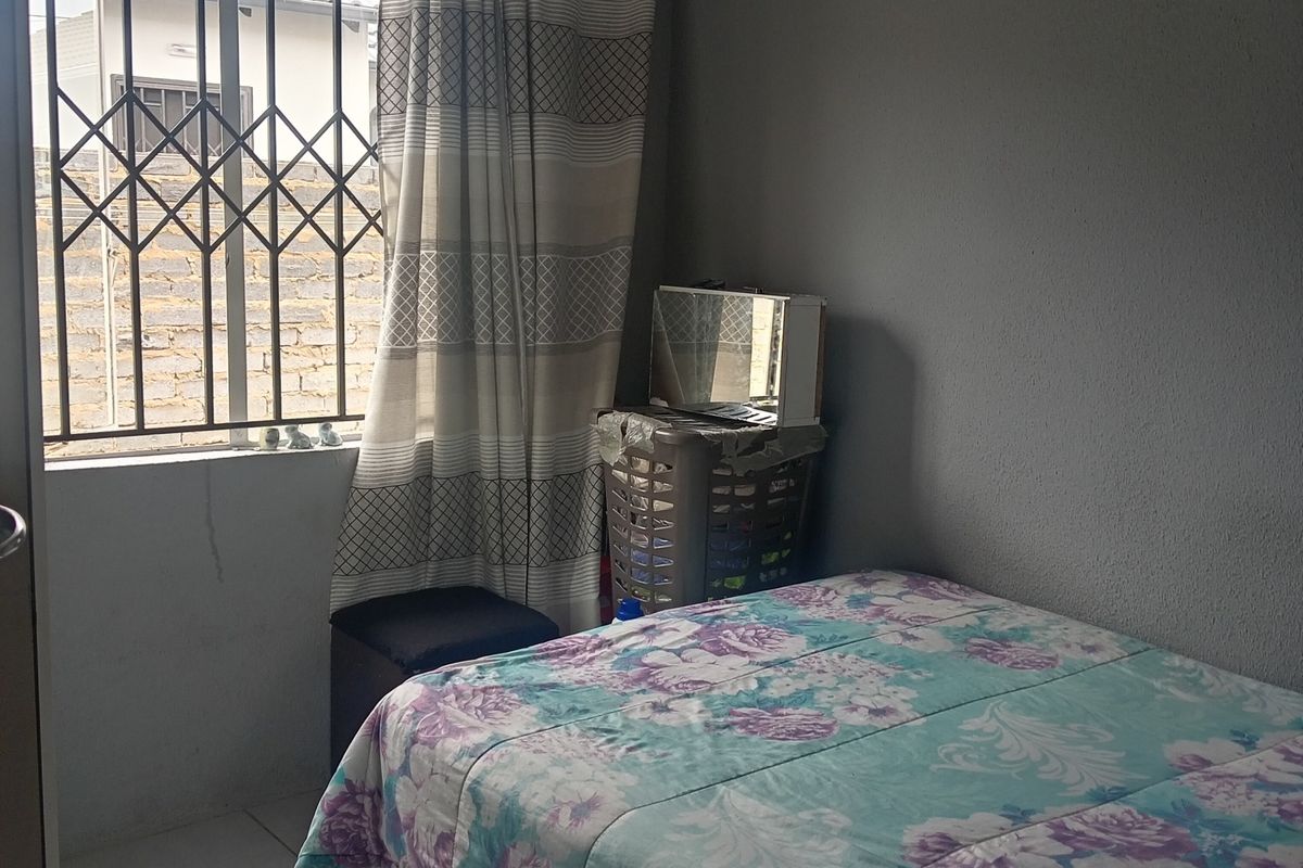 A functional bedroom featuring tiled flooring and a window fitted with a security gate.