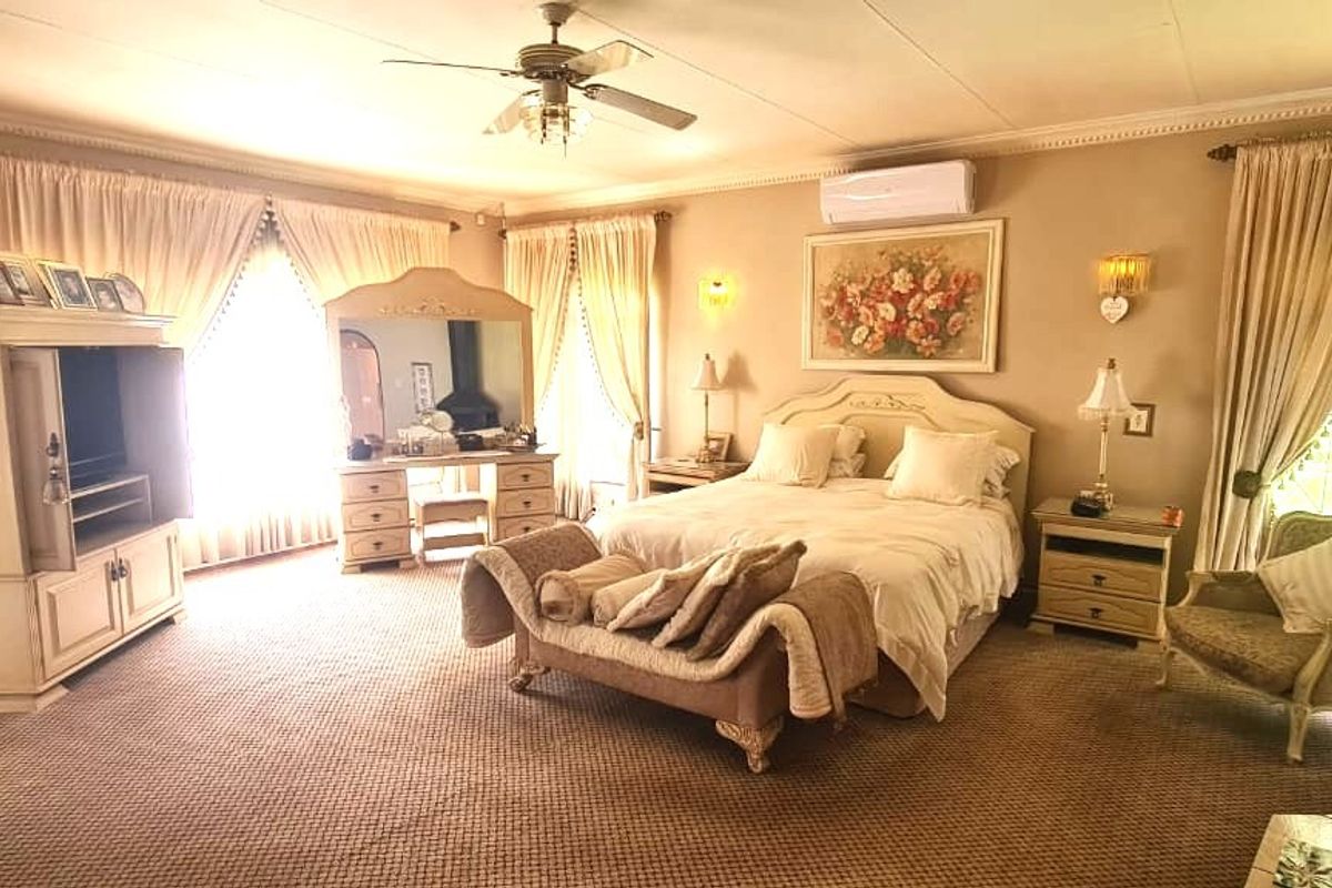 Spacious bedroom featuring a brick accent wall, ceiling fan, and split-system air conditioning unit with large windows providing natural light.