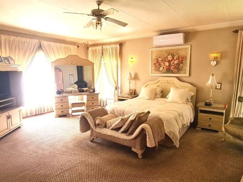 Spacious bedroom featuring a brick accent wall, ceiling fan, and split-system air conditioning unit with large windows providing natural light.