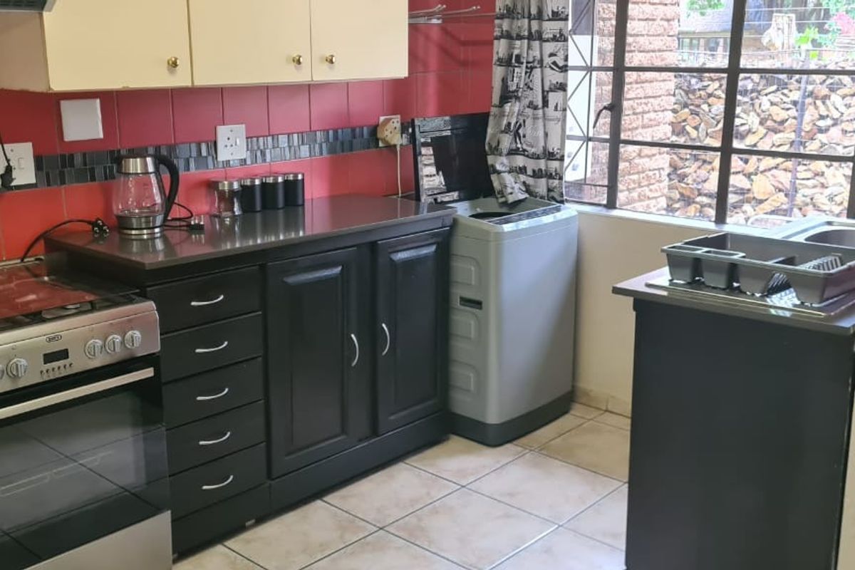 Functional kitchen featuring built-in cabinetry, stainless steel stove, extractor fan, and tiled finishes, offering a practical layout for daily meal preparation.