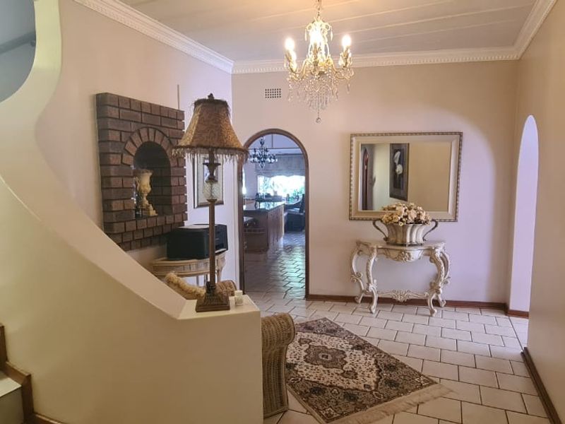 Spacious entrance hall featuring tiled flooring, a grand staircase, and an elegant archway leading into the main living areas of the home.
