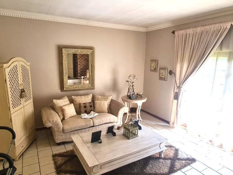 A living room featuring tiled flooring, crown molding, and a sliding glass door providing natural light.