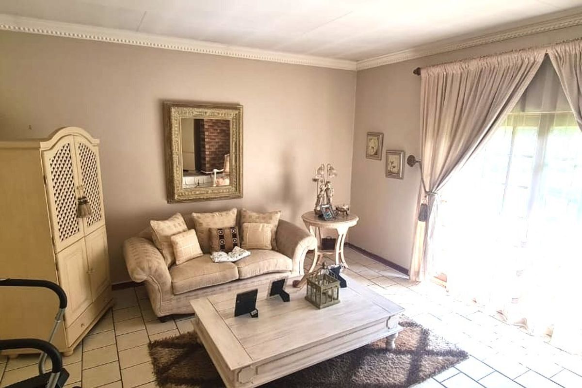 A living room featuring tiled flooring, crown molding, and a sliding glass door providing natural light.