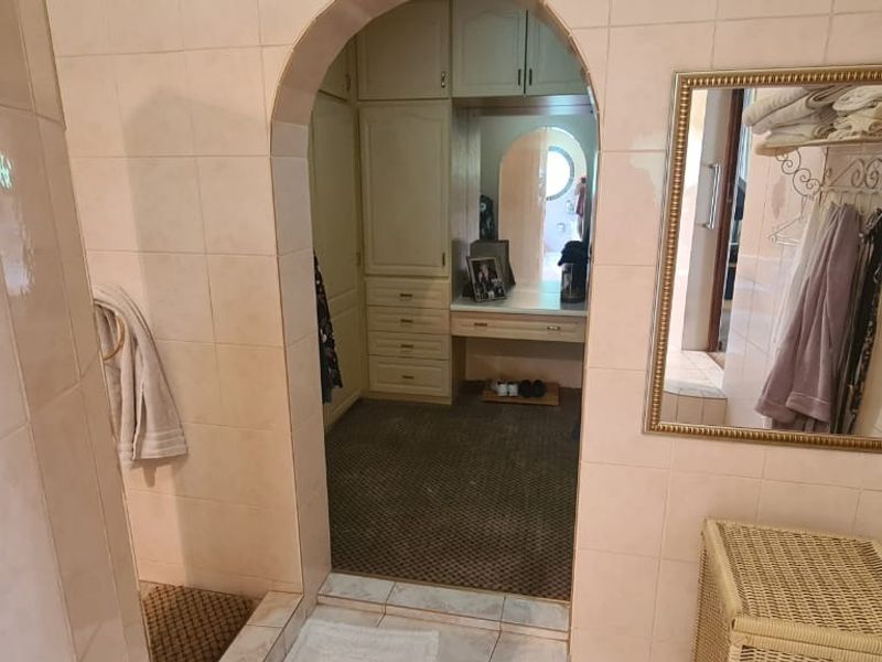 Bathroom featuring tiled walls and an arched entryway leading to a built-in vanity and storage area.