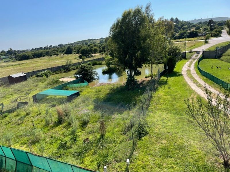 Aerial view of the farm property featuring a gravel driveway, perimeter fencing, and a natural farm dam set within open landscape.