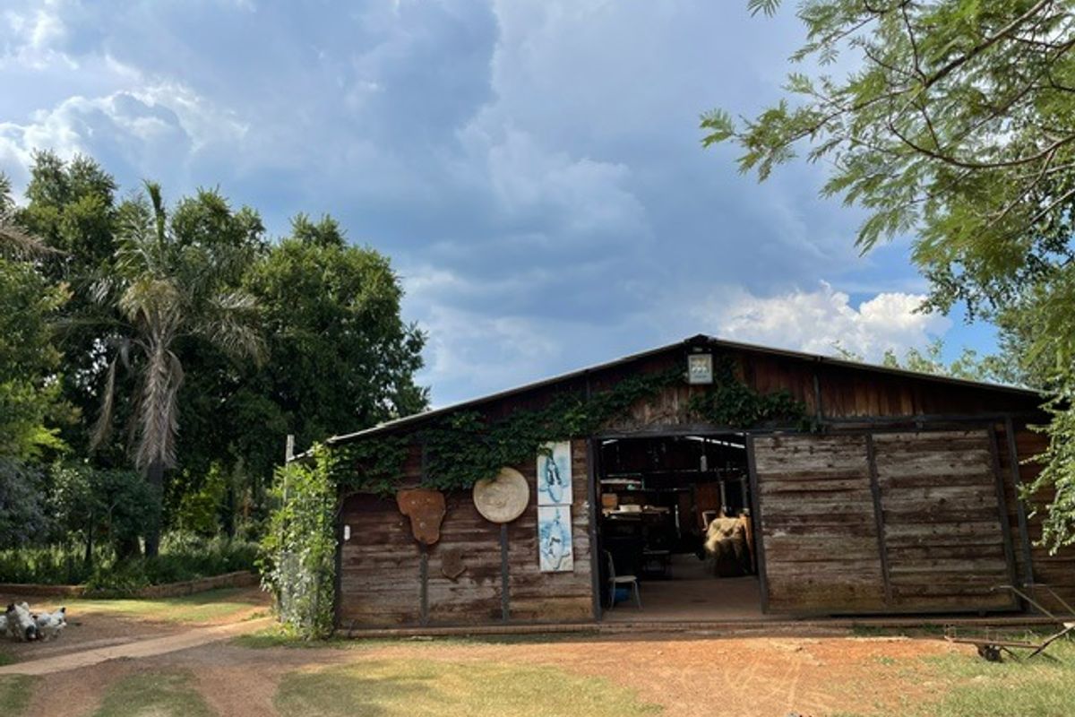 A rustic timber barn structure set within a lush garden, featuring large sliding doors and weathered wood exterior finishes.