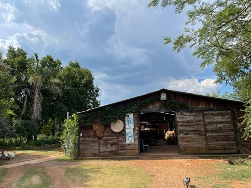 A rustic timber barn structure set within a lush garden, featuring large sliding doors and weathered wood exterior finishes.