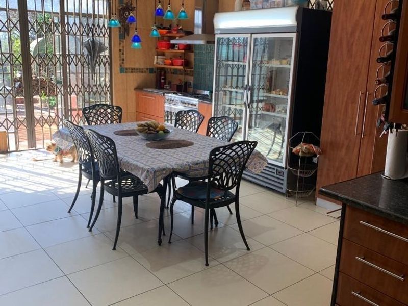Open-plan kitchen and dining area featuring tiled floors, built-in cabinetry, and direct access to an outdoor patio through a security gate.