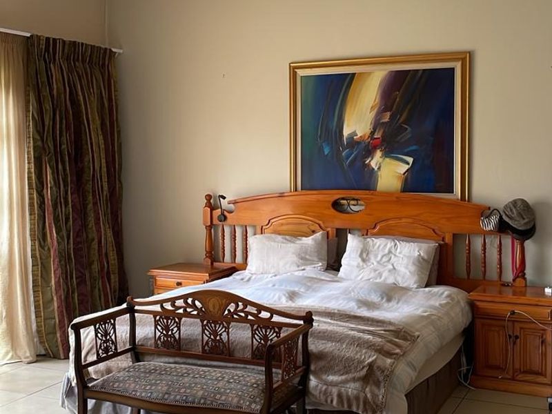 A spacious bedroom featuring neutral wall tones and large format floor tiles, providing a clean and functional foundation for interior design updates.