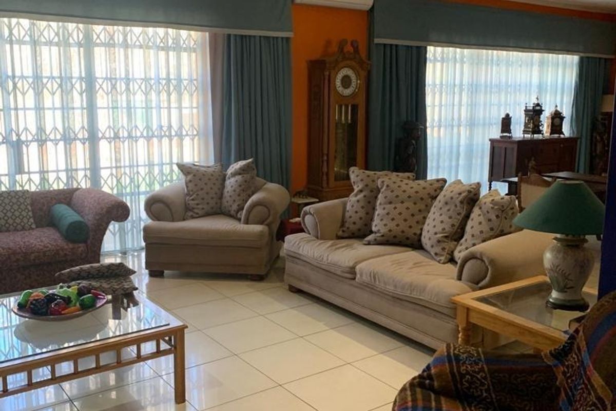 Spacious living room featuring large sliding glass doors with security gates, tiled flooring, and a wall-mounted air conditioning unit.
