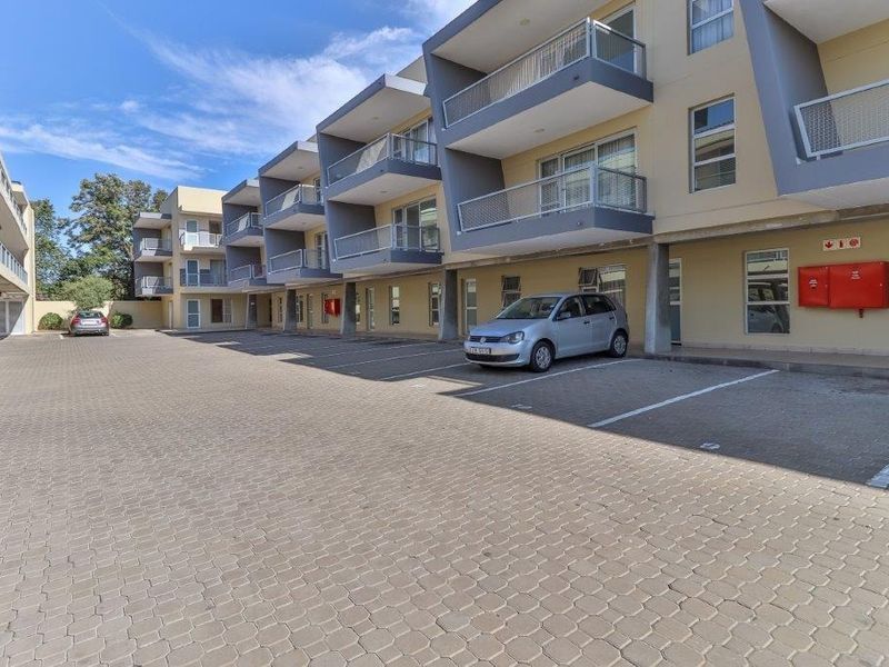 Exterior view of a modern apartment complex featuring paved parking areas and private balconies for each unit.
