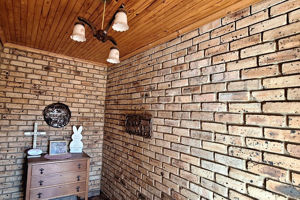 A living area featuring rustic exposed brick walls and a warm timber tongue and groove ceiling, creating a traditional and textured interior space.