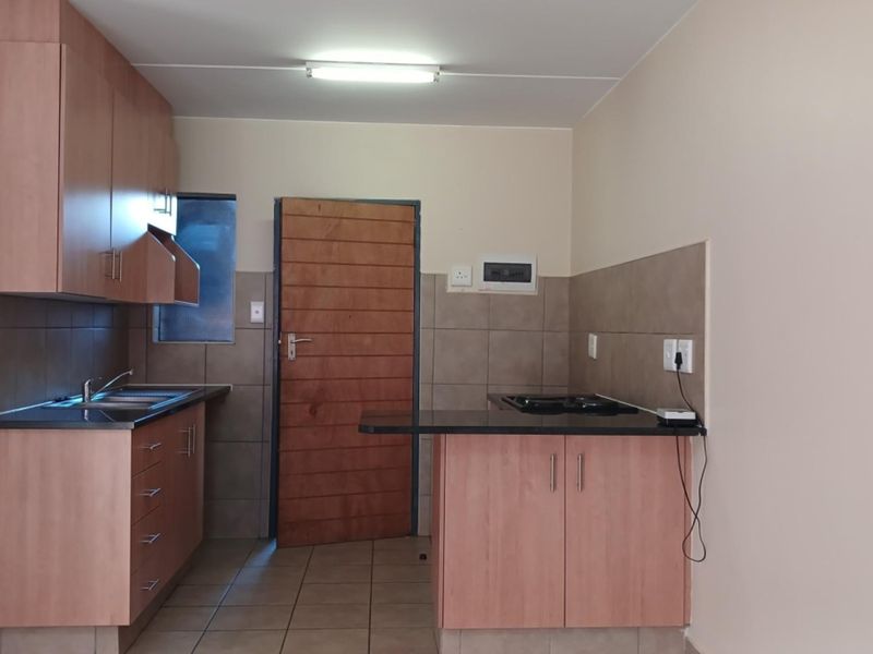 A functional kitchen featuring laminate cabinetry, granite countertops, a built-in hob, tiled backsplash, and tiled flooring, providing a clean and practical workspace.