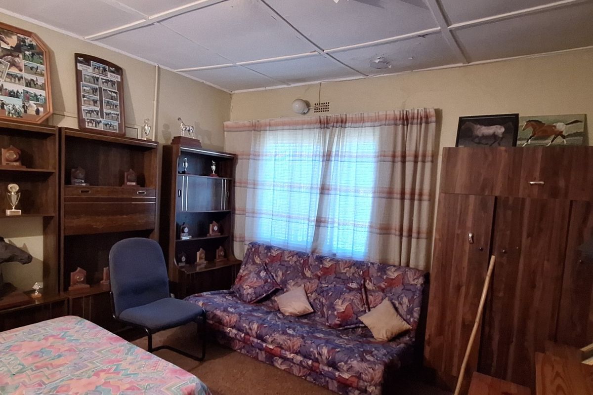 A bedroom featuring built-in wooden cupboards and a tiled ceiling, requiring cosmetic updates to modernize the space.