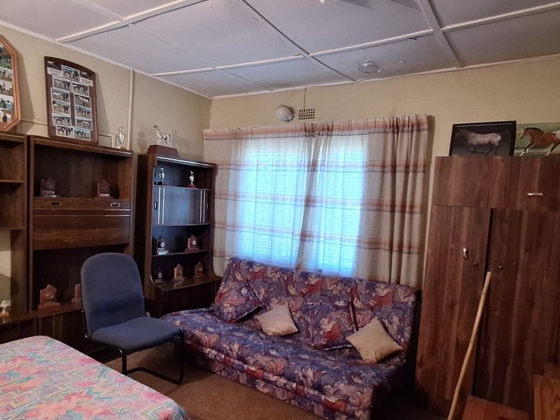 A bedroom featuring built-in wooden cupboards and a tiled ceiling, requiring cosmetic updates to modernize the space.