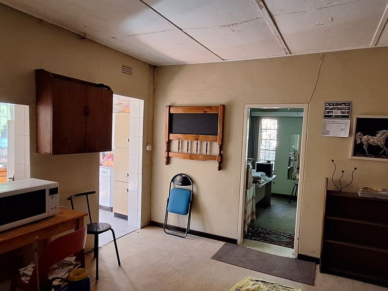 A dated kitchen area featuring built-in stove and cabinetry, showing signs of wear including cracked plaster and ceiling damage, requiring renovation.