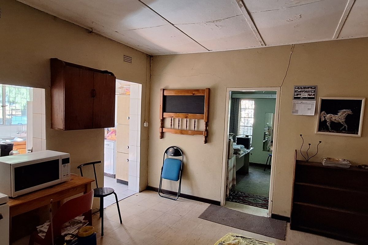 A dated kitchen area featuring built-in stove and cabinetry, showing signs of wear including cracked plaster and ceiling damage, requiring renovation.