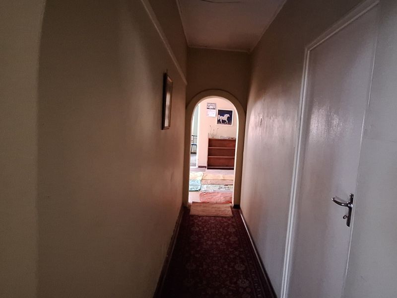 A narrow interior hallway featuring an arched doorway leading to an adjacent room, with plain walls and standard internal doors.