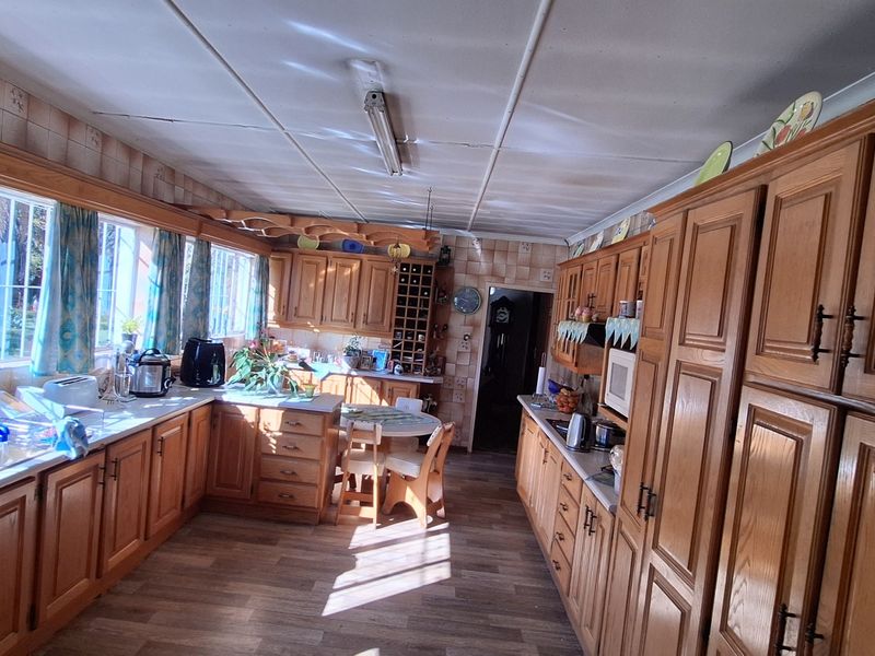 Spacious kitchen featuring extensive wooden cabinetry, laminate countertops, and a double sink, offering ample storage and prep space with a classic layout.