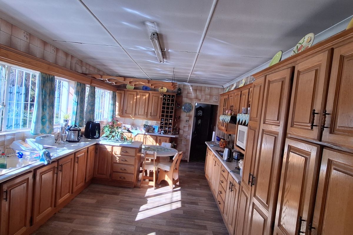 Spacious kitchen featuring extensive wooden cabinetry, laminate countertops, and a double sink, offering ample storage and prep space with a classic layout.