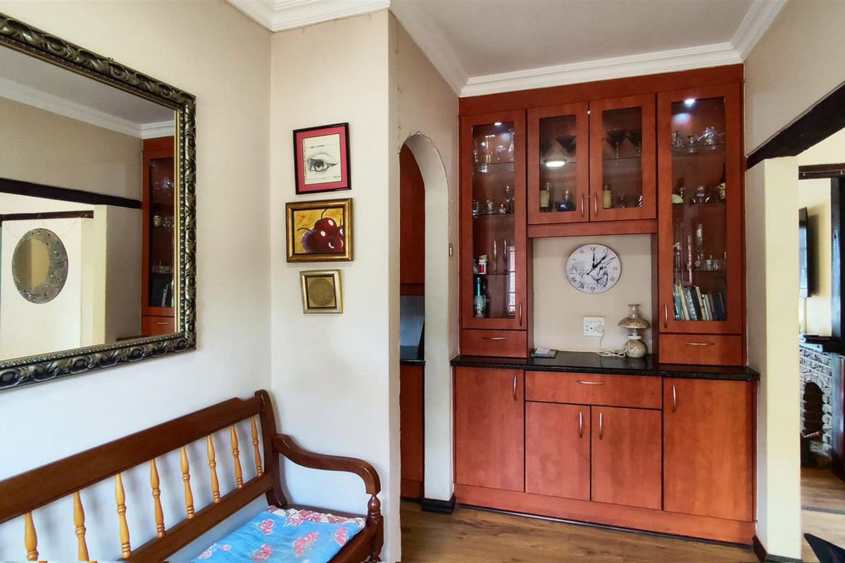 A living area featuring built-in wooden cabinetry with glass display sections, granite countertops, and a decorative archway leading to an adjacent space.