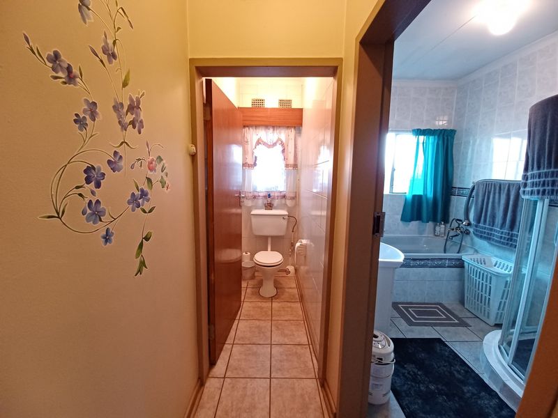 A functional bathroom featuring a separate toilet area, tiled walls and floors, a bathtub, and a shower enclosure.